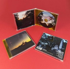CDs in jewel cases with twelve page poster booklets and transparent orange disc trays