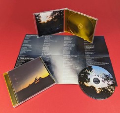 CDs in jewel cases with twelve page poster booklets and transparent orange disc trays