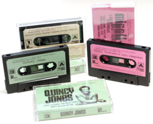 A set of black cassettes with green, pink and cream labels with a selection of music played at Plastic People