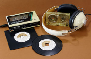 A set of gold glitter cassettes with white on-body printing and black vinyl CDs with a gold print and supplied in plain black record-style wallets