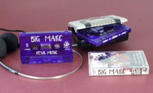 Transparent purple cassette shells with a silver on-body print in clear cases with full colour J-cards