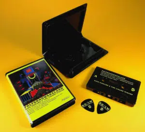 Black cassettes with yellow UV LED printing, supplied in rave cases with printed inserts and matching black guitar picks with yellow UV LED printing