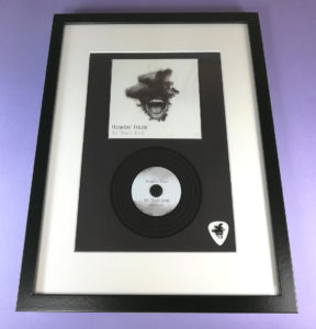 Black presentation frames with vinyl CD and custom guitar pick