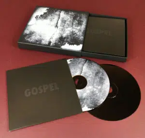 Black matchbox-style CD set with black base discs and matching disc and cover abstract prints