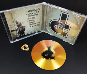 Gold vinyl CDs with gold guitar picks in CD jewel cases