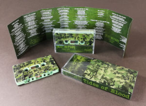 Sage green cassettes with full coverage on-body UV-LED printing and J-cards with five extra fold-out panels, plus outer O-cards over the cases
