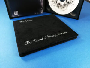 Black velvet hardback digipaks with white cover printing and booklets glued to the inner left panel