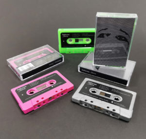 Dark grey recycled, hot pink and slime green cassette tapes in standard tape cases