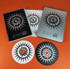 Metal DVD tins with a black on-body print and two CDs inside for The Danse Society