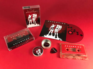 Red glitter cassette tapes, CDs in printed card wallets and guitar picks in printed guitar pick tins