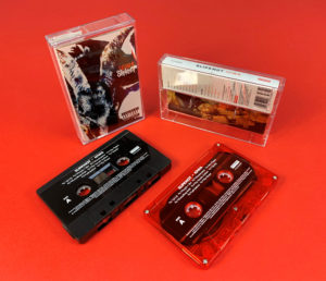 Transparent red and black cassette shells with a white on-body print in clear cases with full colour 6 panel J-cards