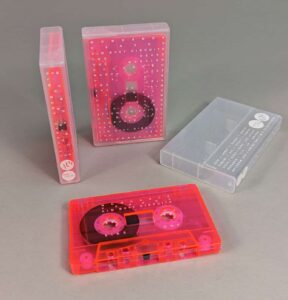 Transparent pink cassette tapes with white on-body printing, packed in clear frosted cases also with white on-body printing