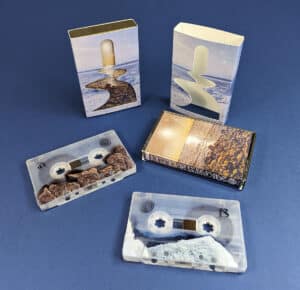 Clear frosted tapes with on-body printing, packed in gold cassette cases with outer O-cards that have a custom shape cutout